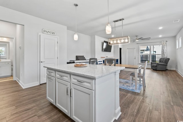kitchen with visible vents, a ceiling fan, baseboards, and wood finished floors
