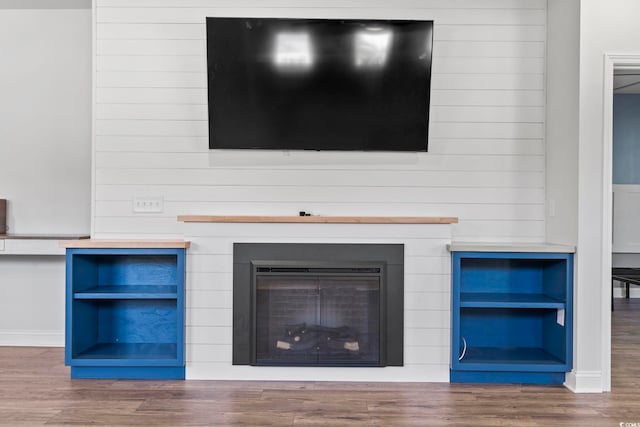 room details with baseboards, wood walls, and wood finished floors