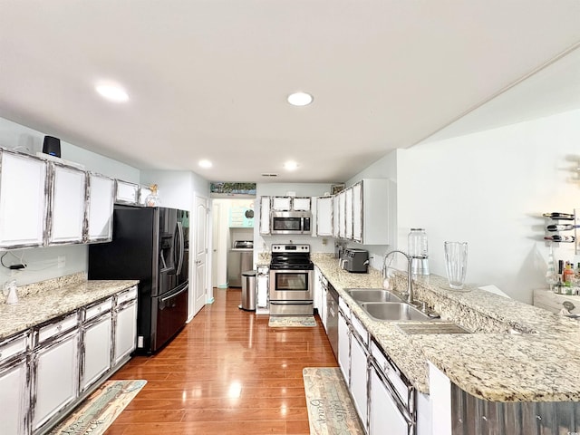 kitchen featuring a sink, white cabinetry, appliances with stainless steel finishes, and a peninsula