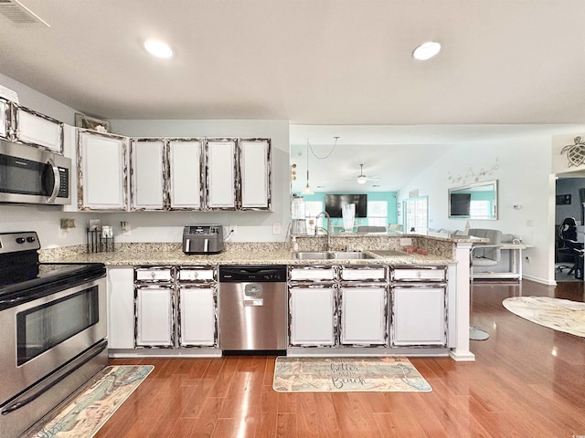 kitchen with visible vents, appliances with stainless steel finishes, a sink, a peninsula, and dark wood-style floors