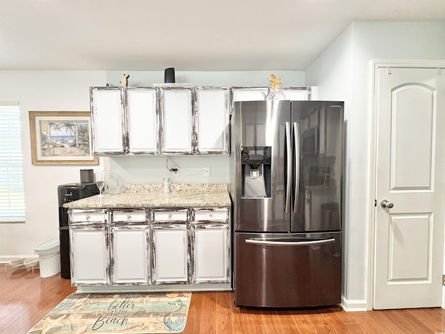 kitchen with white cabinets, baseboards, stainless steel fridge, and light wood finished floors
