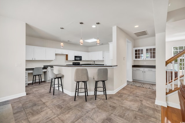 140 Zinnia Dr, Myrtle Beach, SC 29579 - kitchen featuring white cabinetry, a breakfast bar area, visible vents, and black microwave