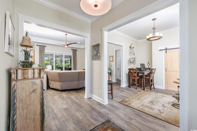 interior space with crown molding, baseboards, a barn door, and wood finished floors