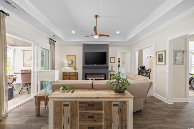 living room featuring visible vents, a fireplace, a tray ceiling, a ceiling fan, and dark wood finished floors