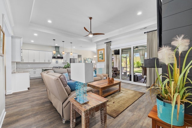 living room with crown molding, ceiling fan, dark wood-style floors, and a raised ceiling