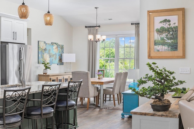 dining room with a chandelier, wood finished floors, and visible vents