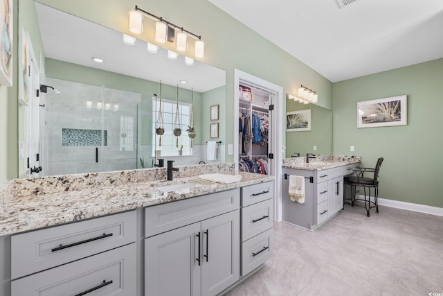 full bath featuring vanity, baseboards, a shower stall, and a walk in closet