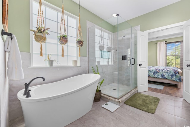 ensuite bathroom featuring tile patterned flooring, a freestanding tub, ensuite bath, and a shower stall