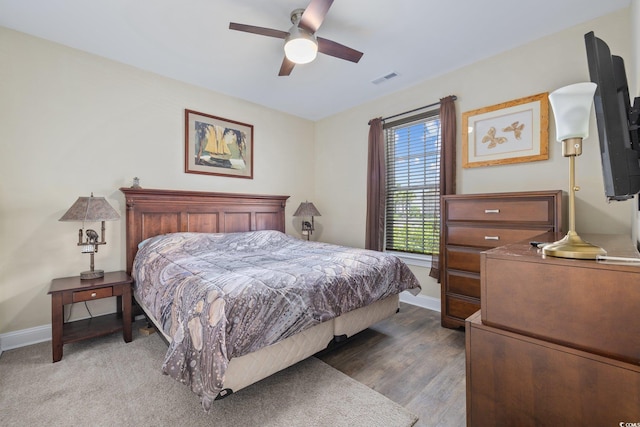 bedroom featuring baseboards, visible vents, ceiling fan, and wood finished floors
