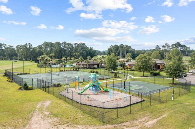 view of tennis court with fence, a yard, and playground community