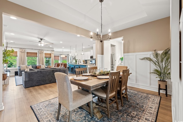 dining area featuring ceiling fan, wainscoting, light wood finished floors, a decorative wall, and recessed lighting