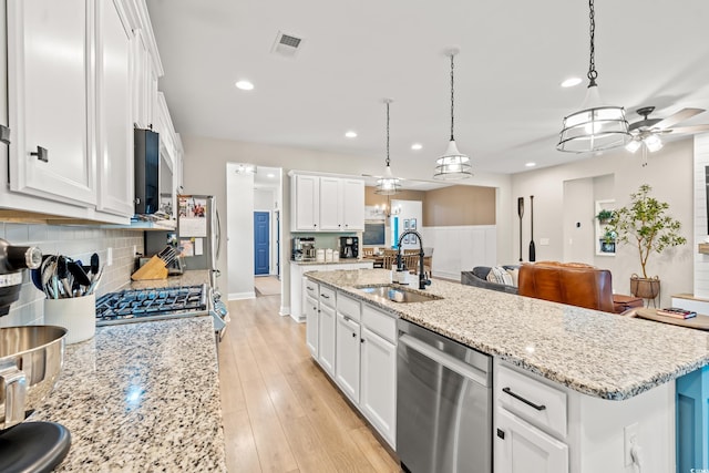 kitchen with ceiling fan, a sink, stainless steel appliances, tasteful backsplash, and visible vents