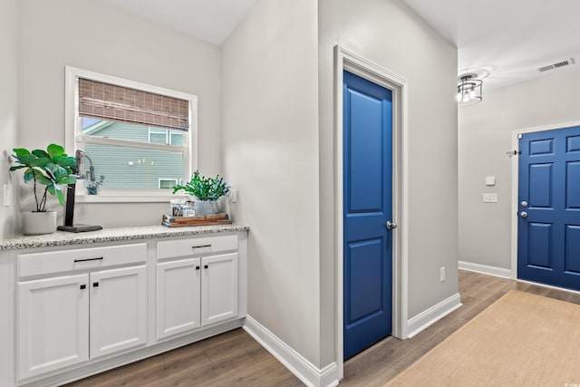interior space featuring baseboards, wood finished floors, and visible vents