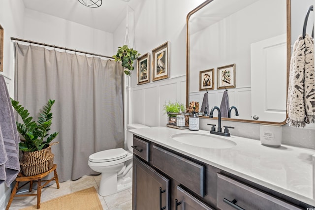 bathroom with a decorative wall, vanity, toilet, tile patterned floors, and a shower with curtain