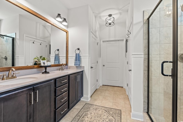 full bath with a sink, tile patterned flooring, a shower stall, and double vanity