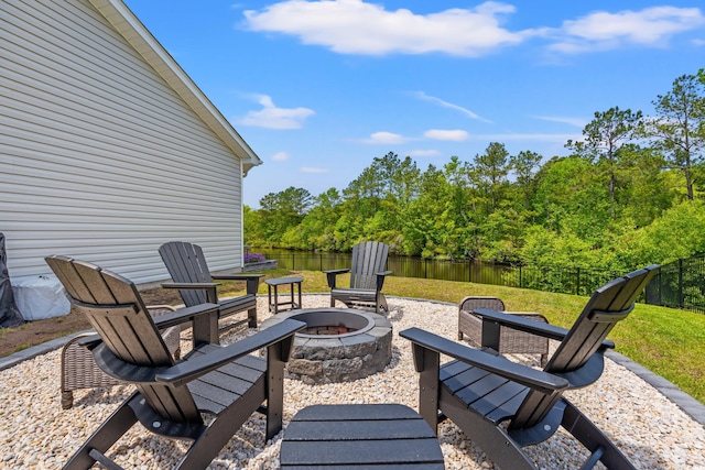view of patio / terrace featuring a water view, fence, and an outdoor fire pit