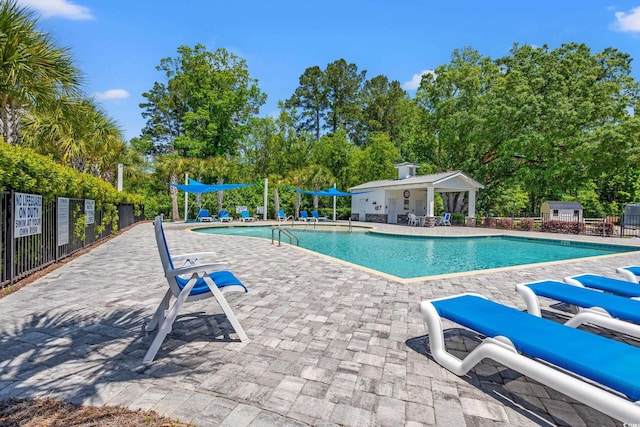 community pool featuring fence, a patio, and an outdoor structure