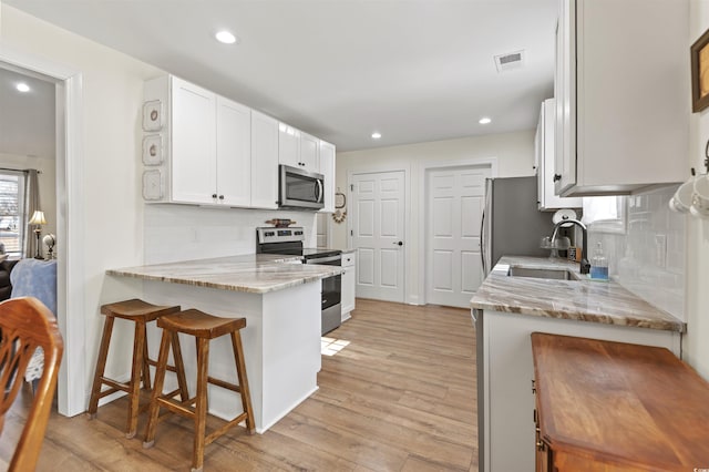 113 Edwards Ln, Longs, SC 29568 - kitchen featuring appliances with stainless steel finishes, a breakfast bar area, white cabinets, light stone countertops, and a sink