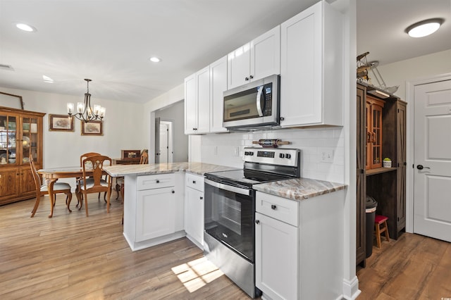 113 Edwards Ln, Longs, SC 29568 - kitchen featuring stainless steel appliances, a peninsula, white cabinets, light wood-style floors, and recessed lighting