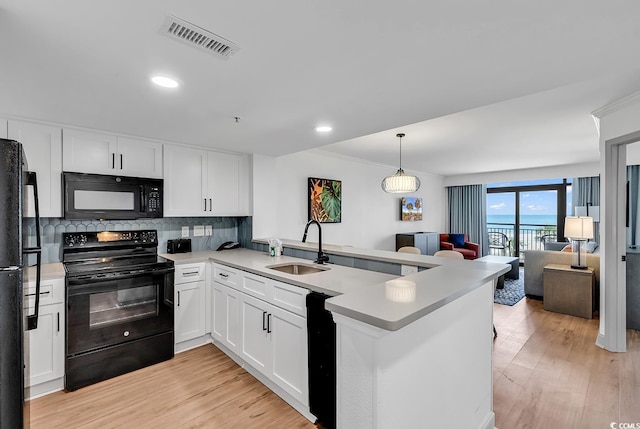 7100 N Ocean Blvd Unit 317, Myrtle Beach, SC 29572 - kitchen featuring black appliances, a sink, a peninsula, open floor plan, and white cabinetry