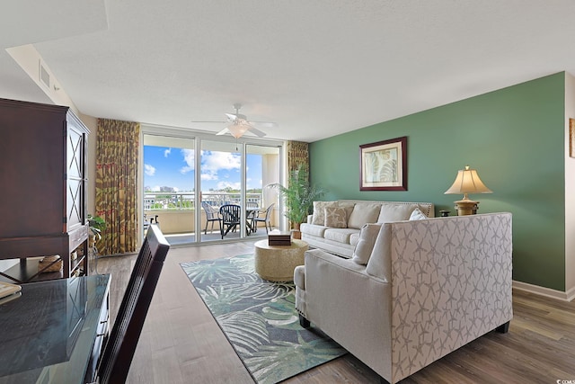 living area with visible vents, a ceiling fan, baseboards, and wood finished floors