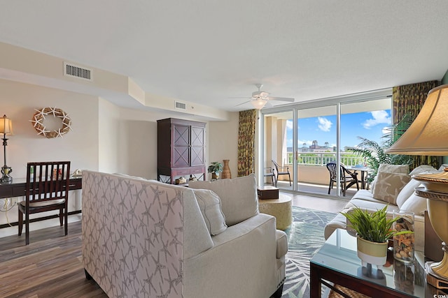 living room featuring a ceiling fan, visible vents, floor to ceiling windows, and wood finished floors