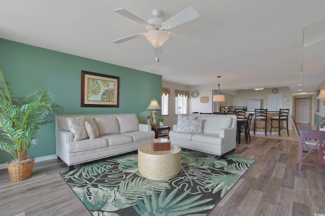 living room with baseboards, a ceiling fan, and wood finished floors