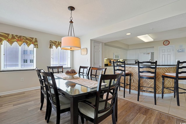 dining area featuring light wood-style floors and baseboards