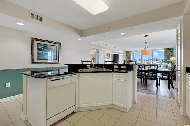 kitchen with visible vents, white dishwasher, dark countertops, pendant lighting, and a sink