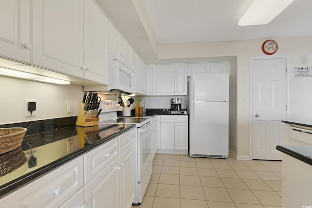 kitchen featuring dark countertops, white cabinetry, light tile patterned floors, and white appliances