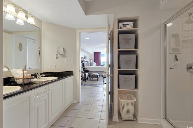full bathroom featuring double vanity, tile patterned floors, a sink, and a stall shower