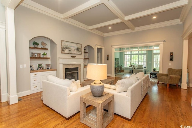 living room featuring crown molding, beam ceiling, a fireplace, coffered ceiling, and light wood finished floors