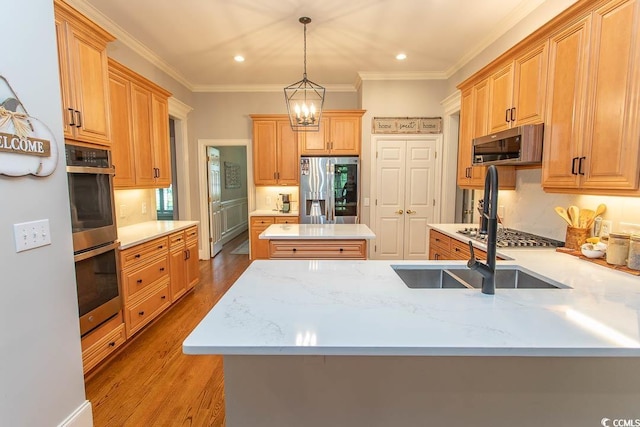 kitchen featuring pendant lighting, a peninsula, wood finished floors, a center island, and appliances with stainless steel finishes
