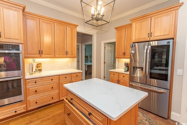 kitchen featuring light wood-style floors, a kitchen island, crown molding, an inviting chandelier, and stainless steel appliances