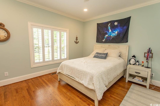 bedroom with baseboards, recessed lighting, crown molding, and wood finished floors