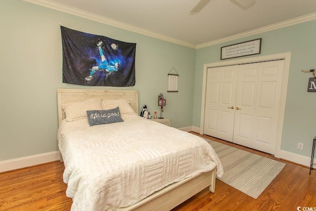 bedroom with baseboards, ornamental molding, a closet, and wood finished floors