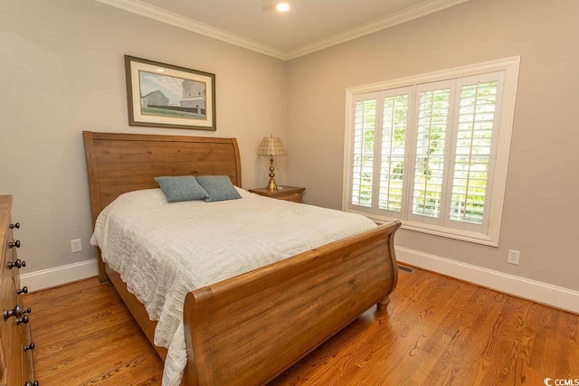 bedroom with baseboards, ornamental molding, wood finished floors, and visible vents