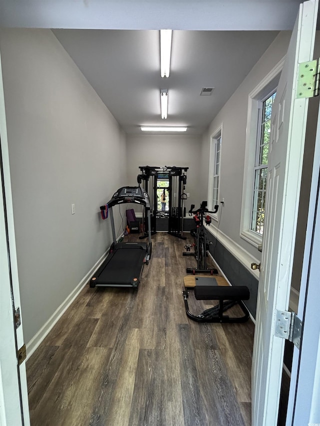 exercise room with baseboards, visible vents, and wood finished floors