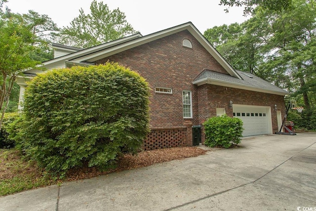 view of side of home with brick siding, a garage, and driveway