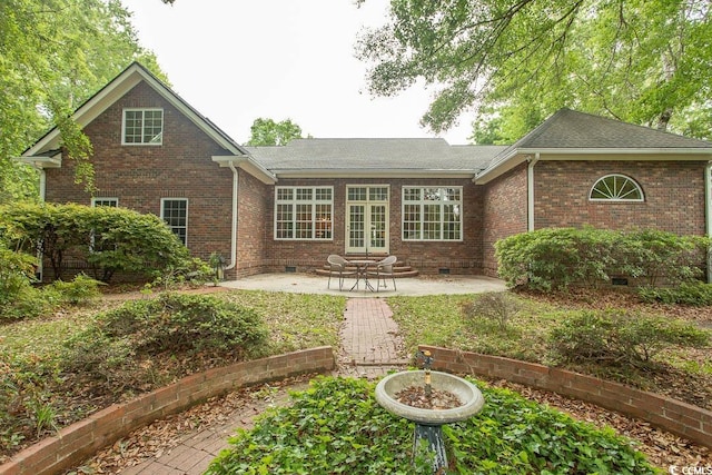 back of house with brick siding, a shingled roof, a patio area, and crawl space