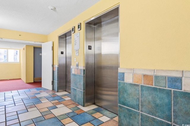 2000 N Ocean Blvd Unit 301, Myrtle Beach, SC 29577 - hall with elevator, a textured ceiling, carpet floors, and a wainscoted wall
