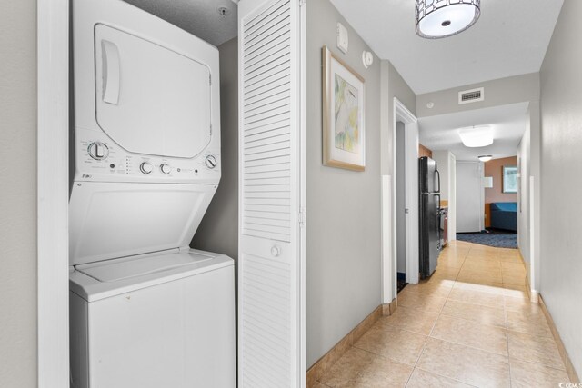 5200 N Ocean Blvd Unit 833, Myrtle Beach, SC 29577 - laundry room with visible vents, laundry area, light tile patterned flooring, baseboards, and stacked washing maching and dryer