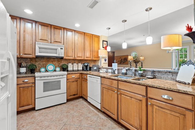 kitchen with white appliances, a sink, light tile patterned flooring, light stone countertops, and brown cabinetry