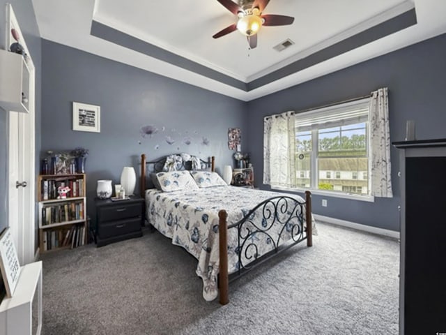 carpeted bedroom with baseboards, ceiling fan, a tray ceiling, and visible vents