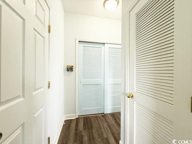 corridor with baseboards and dark wood-style flooring
