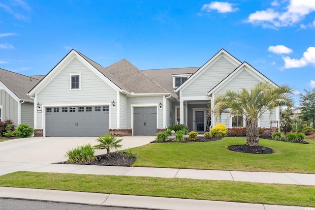 view of front of house featuring a front yard, brick siding, concrete driveway, an attached garage, and a shingled roof