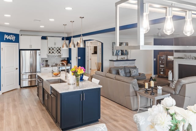 kitchen with freestanding refrigerator, a sink, arched walkways, and open floor plan