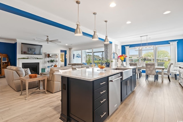 kitchen featuring ceiling fan, stainless steel dishwasher, a sink, open floor plan, and light wood-style floors