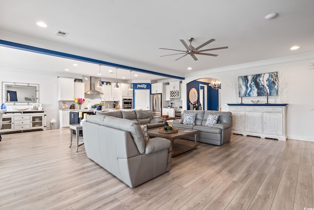 living room featuring arched walkways, ceiling fan, light wood-type flooring, and visible vents