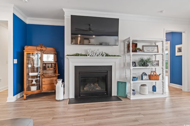 living area with baseboards, a fireplace with flush hearth, ornamental molding, and wood finished floors